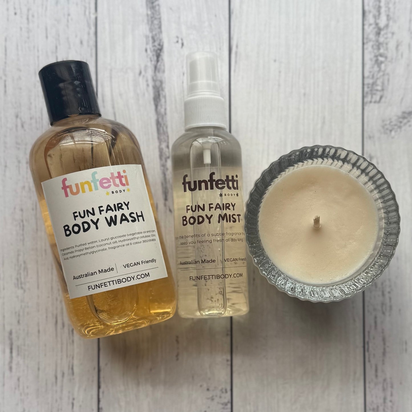 Three skincare products from Funfetti Body on a wooden surface: body wash, body mist, and candle.