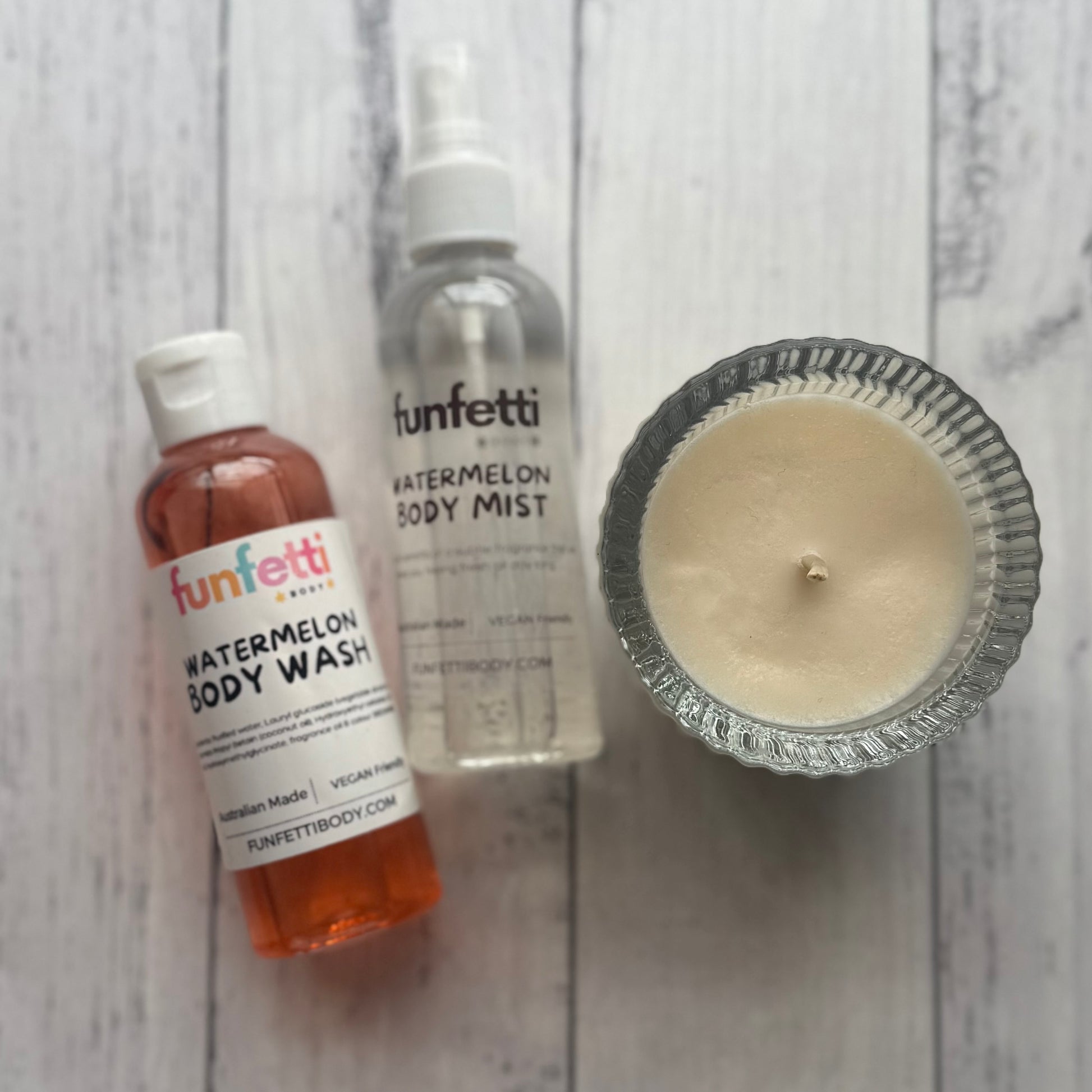 Funfetti watermelon body wash, mist, and candle on a wooden surface